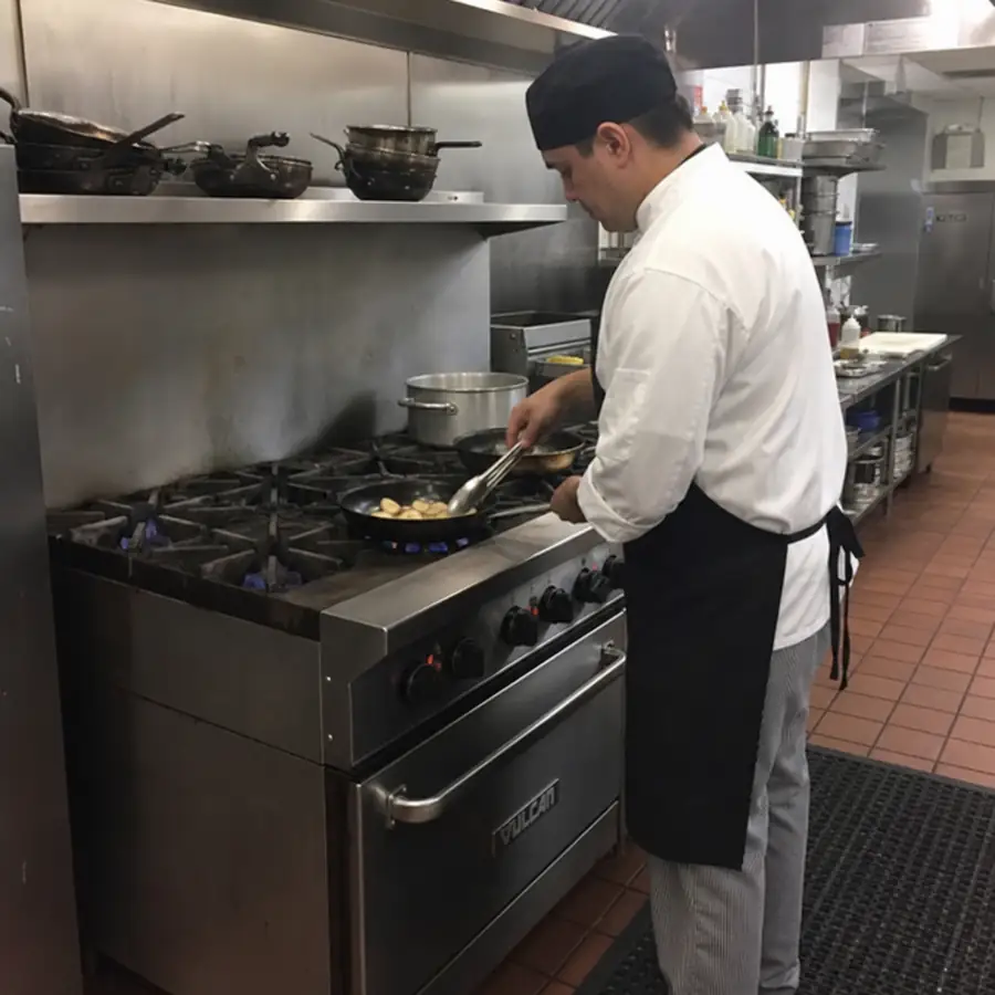 Chef cooking on a heavy-duty commercial six-burner range in a restaurant kitchen