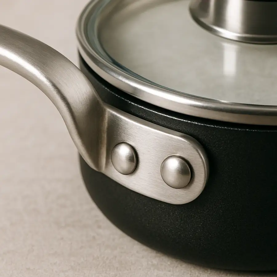 Close up of a professional riveted pan handle and a tempered glass lid