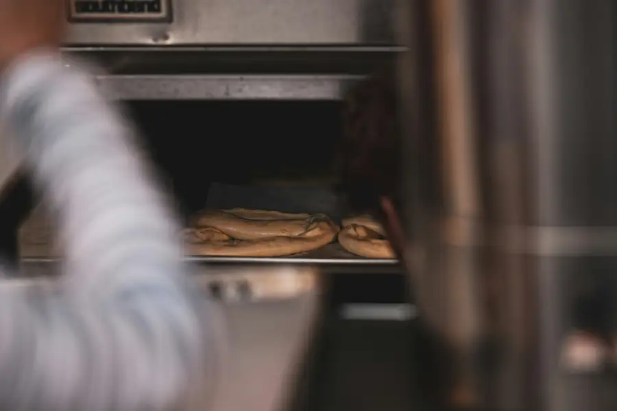 An image depicting restaurant staff cleaning a pizza oven