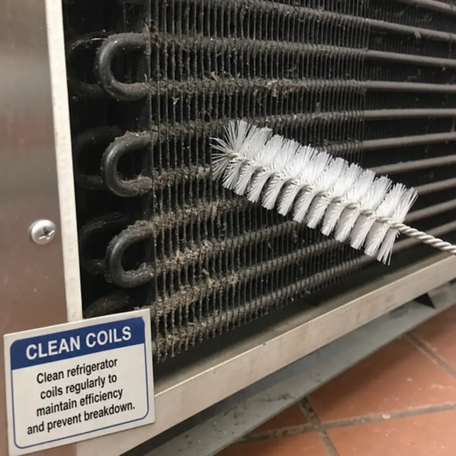 Close up of commercial refrigerator coils and cleaning brush in English