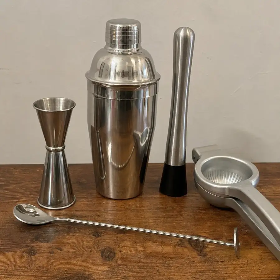 Essential bartender tools including cocktail shaker, jigger, bar spoon, muddler, and citrus juicer