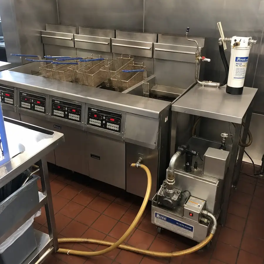Commercial kitchen deep fryer station with fry baskets, oil vats, and cooked fried foods ready for service