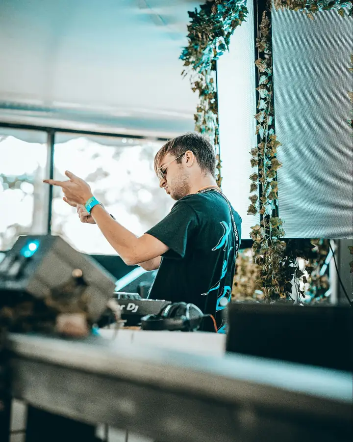 DJ performing at an outdoor event booth with a Pioneer controller, headphones, and an LED backdrop, illustrating food truck event marketing