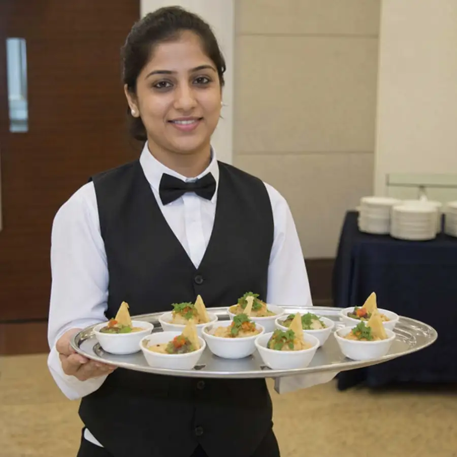 Server presenting appetizers on a Thunder Group stainless steel serving tray with mirror finish at a banquet