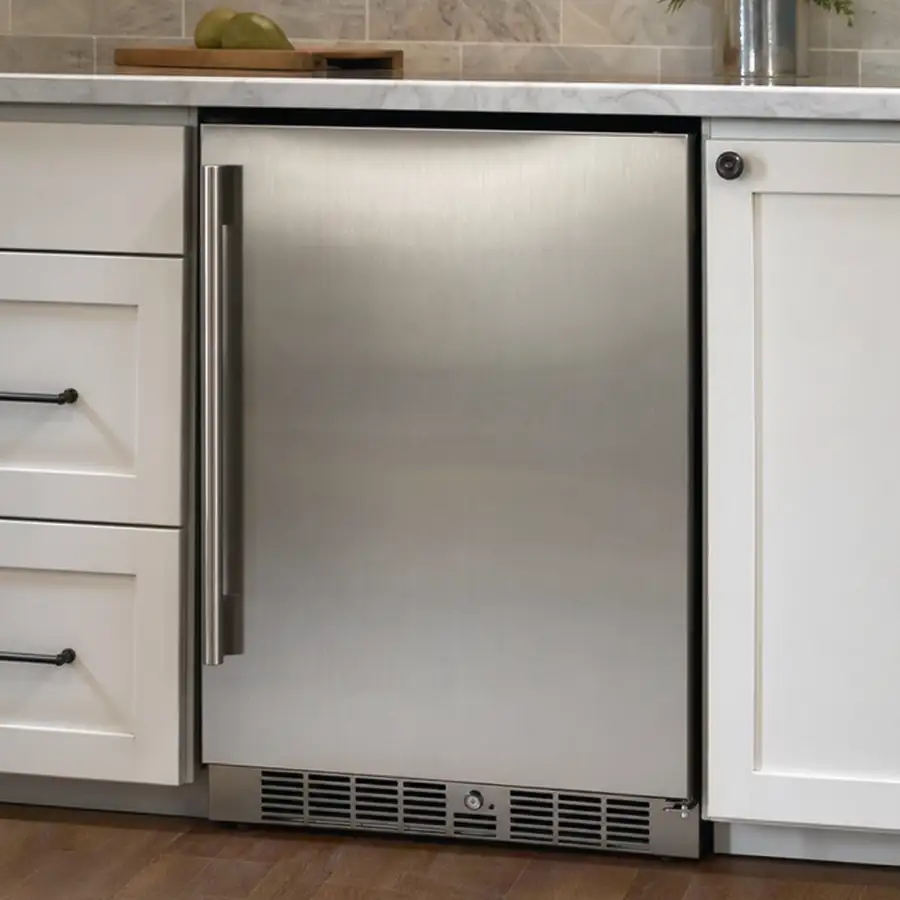 Stainless single-door undercounter refrigerator built into white kitchen cabinets under a marble counter, with a bottom vent grille